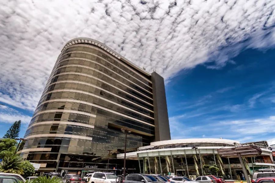 Fachada del Edificio Sixtino I, torre curva de vidrio dorado con locales comerciales en la planta baja, en la zona 10 de la Ciudad de Guatemala